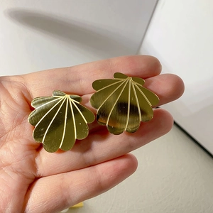 Detail of 18k gold plated titanium steel shell earrings with a brushed metal texture