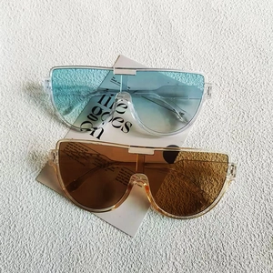 Close-up of semi-rimless sunglasses in sky blue and tea brown on a textured card