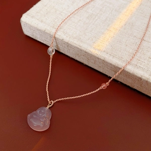 Macro detail of translucent pink chalcedony Buddha pendant with woven rope necklace