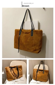 Detail of large brown plush tote bag with black leather straps on a warm background