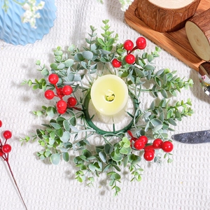 Christmas red berry candle ring with green leaves and yellow pillar candle on a tablecloth