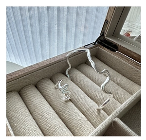 Detailed view of silver wavy jewelry set featuring a ring and bracelet in a wooden box