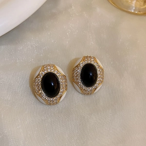 Detailed macro of vintage gold earrings with black oval stones and diamond halo on silk