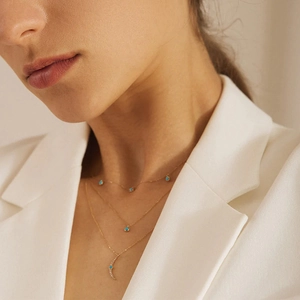 Close-up of triple-layered gold necklaces with turquoise accents and crescent pendant