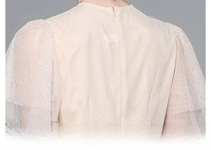 Detail of the invisible back zipper on a cream mesh dress with polka dots and puff sleeves