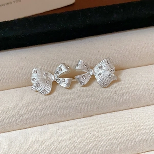 Macro shot of silver bow stud earrings with sparkling zircons on a beige velvet display