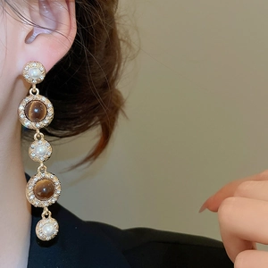 Close-up of vintage drop earrings with pearls, brown tiger eye stones and crystals