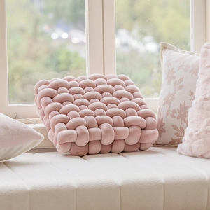 Pink velvet knot square pillow with hand-woven texture on a cozy window seat