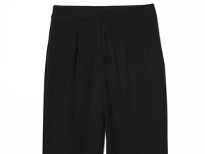Detail of high-waist pleated design and hidden placket on black tailored trousers