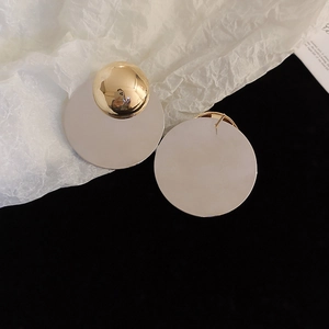 Macro shot of gold and silver mixed-metal round geometric earrings with mirror finish