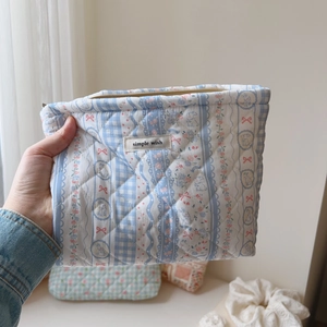 Detail of light blue quilted cosmetic bag with floral patterns and bunny illustrations