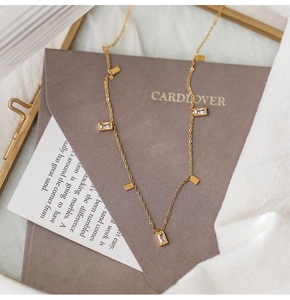 Close-up of golden titanium necklace with crystal square pendants on white fabric
