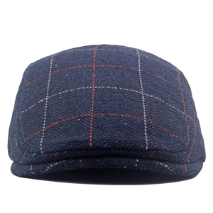 Detailed close-up of dark blue herringbone tweed fabric on a British newsboy cap