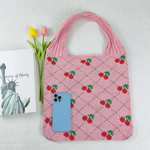 Close-up of pink knit tote bag featuring cherry jacquard pattern and texture details