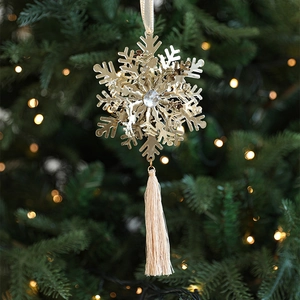 Gold metal snowflake ornament with central crystal and tassel on a Christmas tree