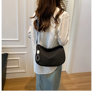 Detail of black crescent canvas crossbody bag with branded wide strap on casual outfit
