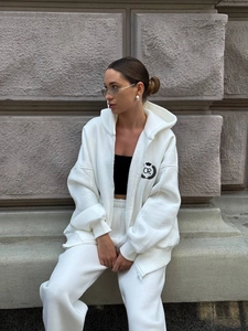 Detail of white hooded tracksuit with zip jacket and pants showing relaxed fit on model