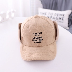 Detail of beige fleece baseball cap with earflaps and embroidered London Paris text