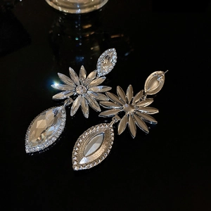 Macro view of long silver flower drop earrings with sparkling rhinestones on black background