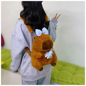 Rear view of a model wearing the brown Capybara plush backpack with a blue plaid bow tie