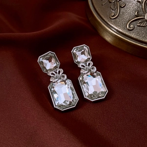 Détail de boucles d'oreilles nœud argentées avec cristaux sur un tissu en soie rouge