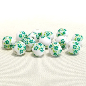 Detail of 10mm white ceramic beads with green floral pattern on textured fabric