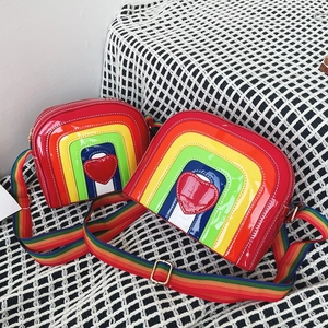 Detailed view of rainbow striped crossbody bags with heart patches and wide fabric straps