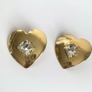 Detailed close-up of gold heart earrings with square crystal in a minimalist setting