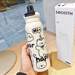 Close-up of 620ml cream stainless steel insulated cup with cartoon bear pattern in hand
