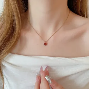 Elegante collana dorata con ciondolo a cuore in cristallo rosso su una modella