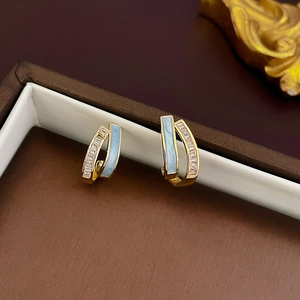 Details von C-förmigen Goldohrringen mit blauem Emaille und rosa Zirkon-Steinen