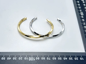 Detailed top view of twisted stainless steel cuff bangles in gold and silver finishes