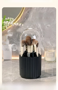 Detail view of a rotating makeup brush organizer with dust-proof cover on marble top