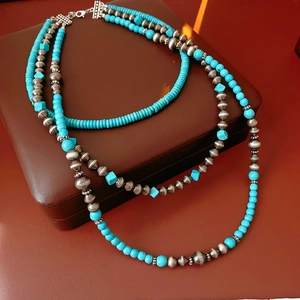 Dettaglio della collana multistrato in turchese e metallo su un portagioie in pelle marrone