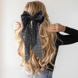Barrette élégante nœud à paillettes noires avec longs rubans sur cheveux blonds