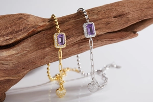 Macro detail of rectangle purple gemstone bracelets with heart pendants on wood