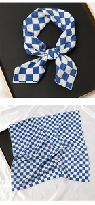 Détail d'un foulard en soie à carreaux bleus et blancs sur un plateau noir et tissu en soie