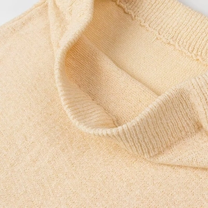 Vista macro dettagliata della scollatura in maglia a coste beige e delle cuciture del top senza maniche
