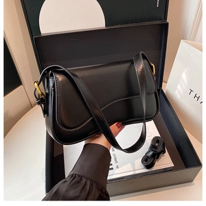 Detail of a black shiny shoulder bag with vintage gold hardware and extra strap