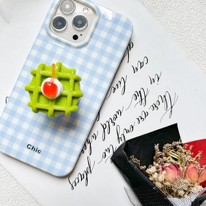 Detail of 3D waffle and cherry phone grip on a blue checkered case with Chic text