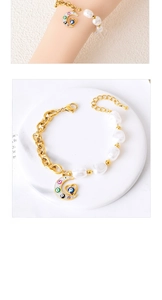 Detail of gold chain pearl bracelet with crescent moon and evil eye heart charms