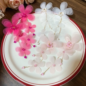 Macro view of floral chiffon tassel earrings in pink and white on a ceramic plate