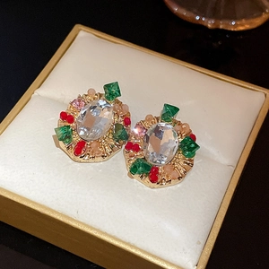 Macro shot of vintage gold earrings with green and red gems in a beige gift box