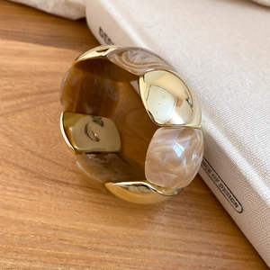 Detailed view of wide chunky bracelet with gold metal plates and marbled resin blocks
