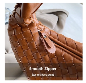Detail showing the intricate brown woven leather texture and smooth metal zipper closure