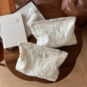 Détail de la trousse à maquillage en dentelle blanche brodée avec motifs floraux