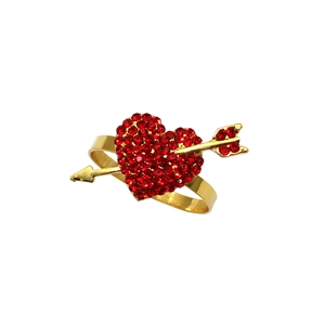 Close-up of golden napkin ring featuring a red rhinestone heart with a gold arrow detail