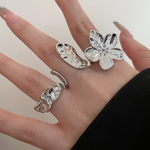 Detail of silver irregular floral and lava textured rings worn on a hand for luxury style