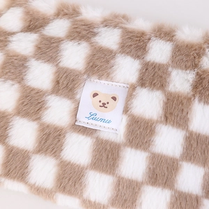 Detail of plush checkered makeup bag featuring soft fuzzy texture and cute bear logo