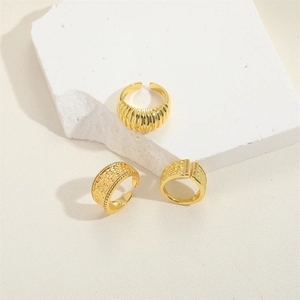 Three gold croissant style rings with textured hammer finish on a decorative stone base
